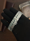 Premium men's silver watch bracelet with modern links, displayed by gloved hand on wooden table