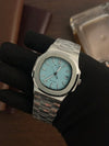 Luxury men’s silver watch with blue dial, showcased on a gloved hand, premium timepiece