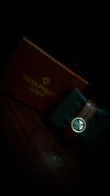 Luxury men's watch with brown leather strap and Patek Philippe box on dark wood, premium design